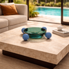 Modern living room with a coffee table, sofa, and view of a pool and garden.