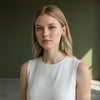 Woman wearing green earrings against a neutral background