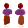 Pair of colorful earrings with red, purple, and brown components on a white background