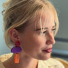 Close-up of a person wearing colorful earrings with a blurred background