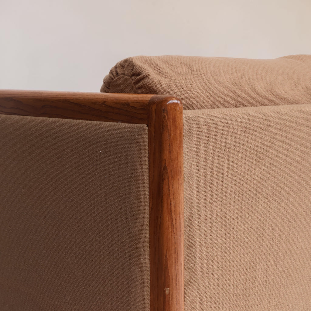 Image features the corner of a brown mid-century modern wool sofa with a wooden frame against a white background.