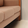 Image features a close up of the cushions of a brown mid-century modern wool sofa with a wooden frame against a white background.