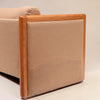Image features a close up of the side of a brown mid-century modern wool sofa with a wooden frame against a white background.