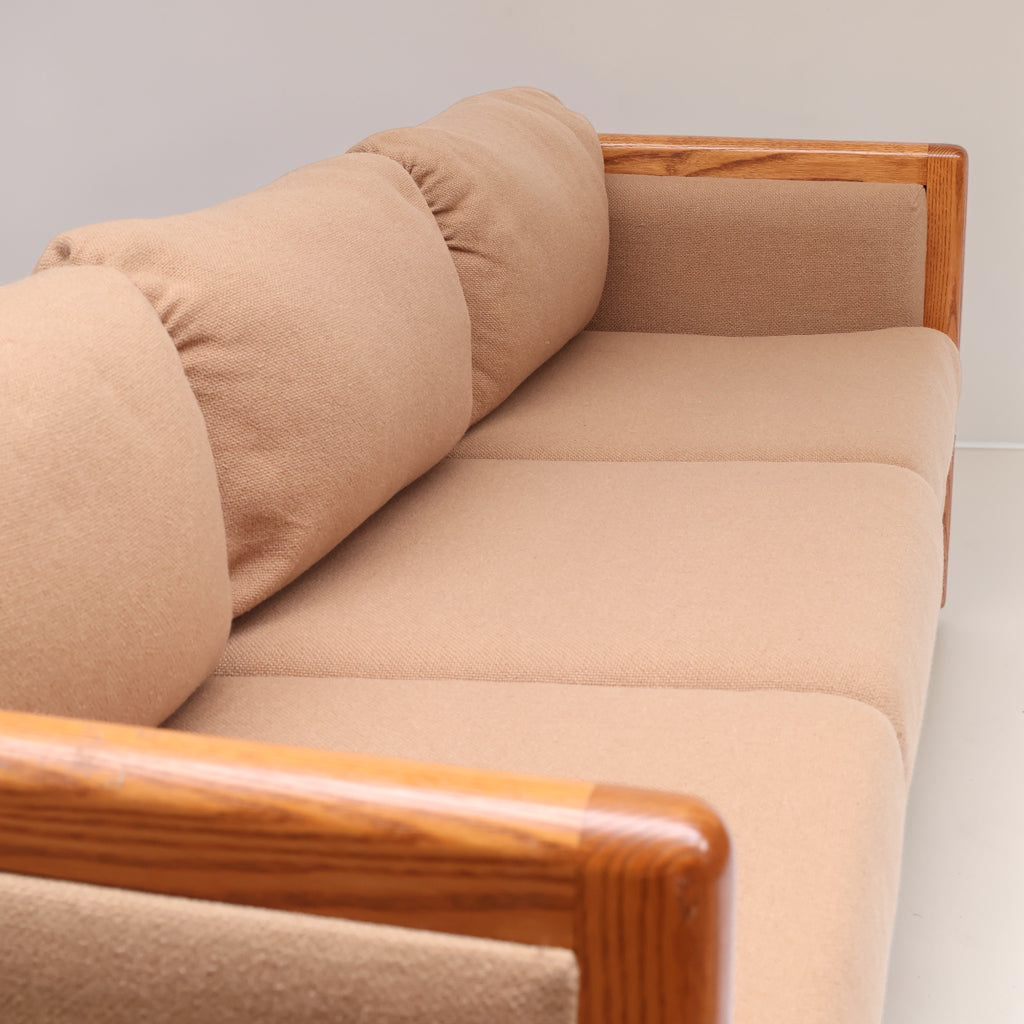 Image features the cushions of a brown mid-century modern wool sofa with a wooden frame against a white background.
