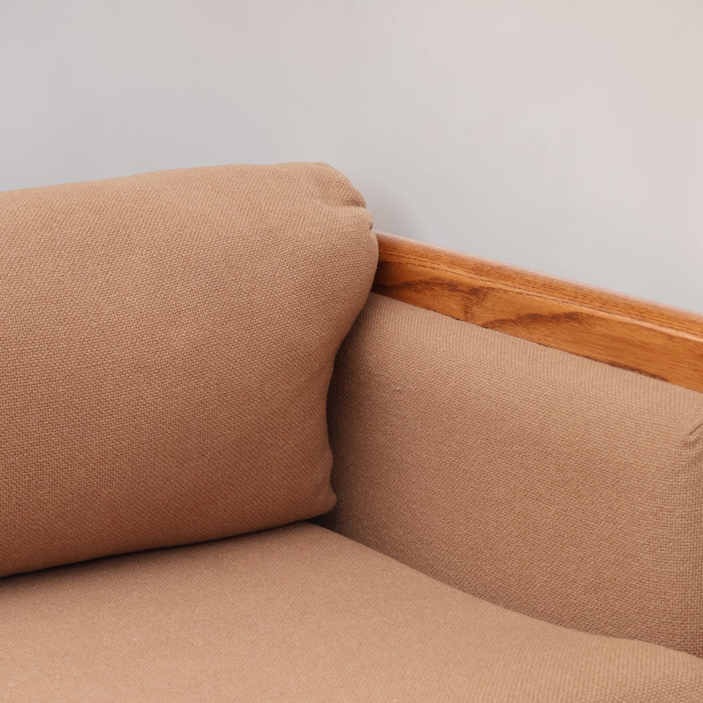 Image features the corner cushion of a brown mid-century modern wool sofa with a wooden frame against a white background.