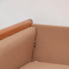 Image features the corner of a brown mid-century modern wool sofa with a wooden frame against a white background.