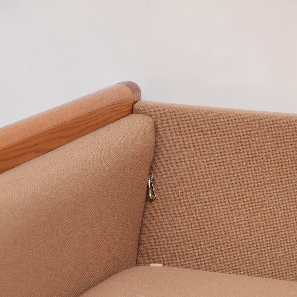 Image features the corner of a brown mid-century modern wool sofa with a wooden frame against a white background.