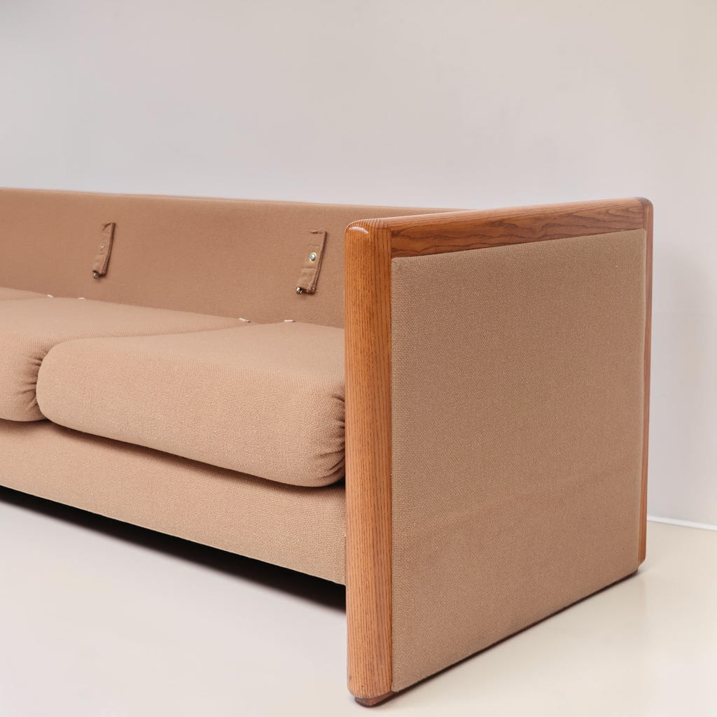 Image features the side of a brown mid-century modern wool sofa with a wooden frame against a white background.