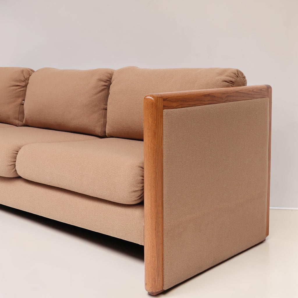 Image features the side of a brown mid-century modern wool sofa with a wooden frame against a white background.