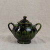 Green ceramic teapot with lid on a gray background