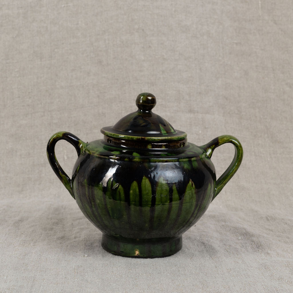 Green ceramic teapot with lid on a gray background