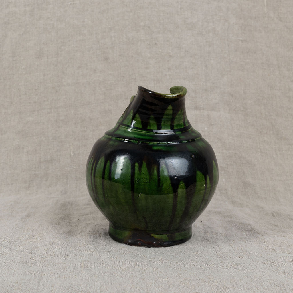 Green ceramic vase on a textured beige background