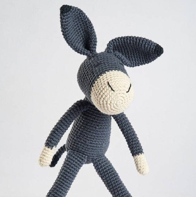 Crocheted donkey toy on a light gray background