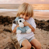 Child holding a stuffed animal on a beach at sunset
