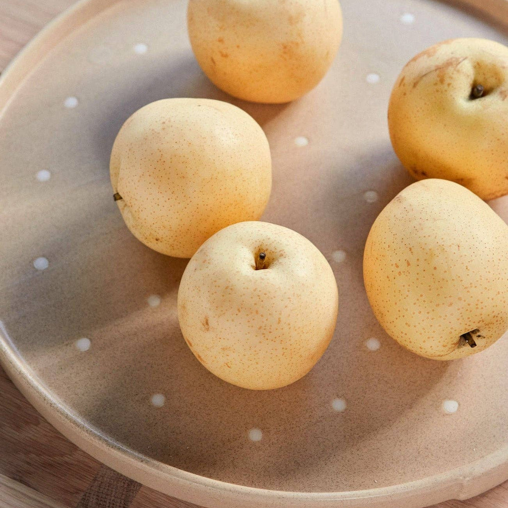Five apples on a ceramic plate with a polka dot pattern