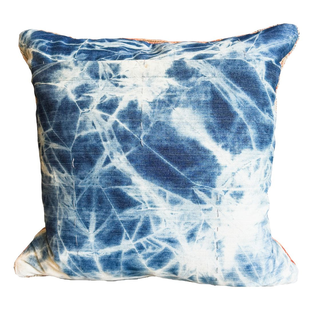 Decorative pillow with blue and white tie-dye pattern on a white background