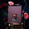 Book titled 'Once Upon a Time' surrounded by flowers and books on a dark background