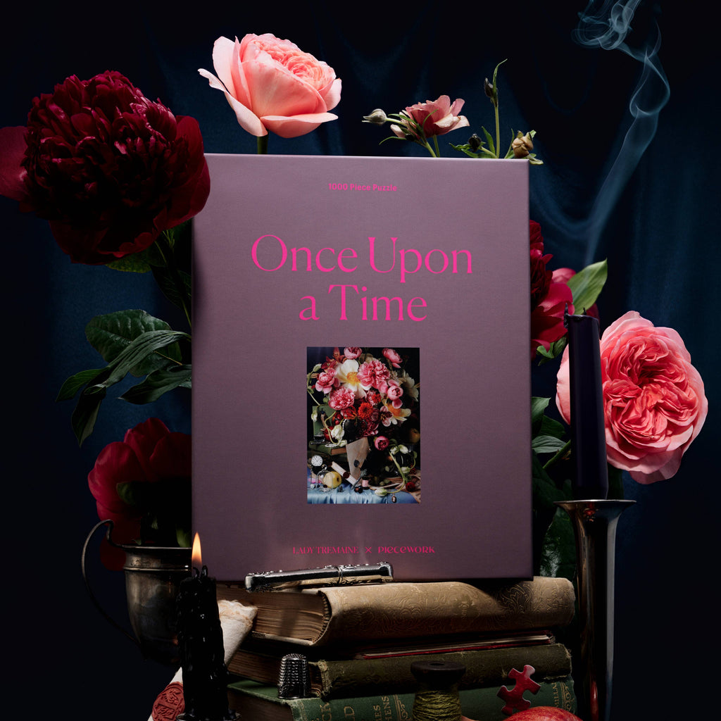 Book titled 'Once Upon a Time' surrounded by flowers and books on a dark background