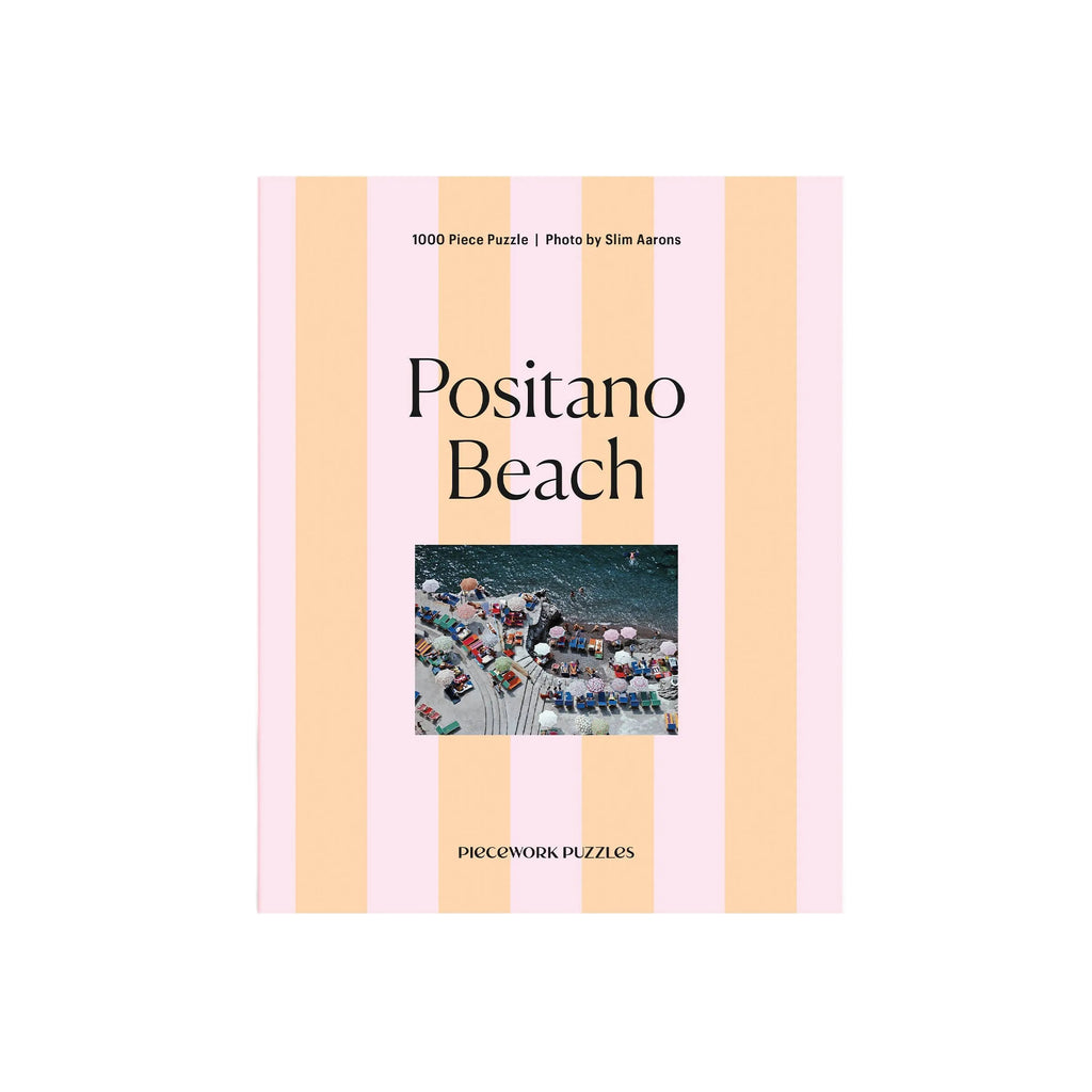 Piecework Puzzle Co. Positano Beach puzzle packaging with striped design and photo of beach scene.