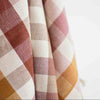 Close-up of checkered fabric with red, white, and orange pattern on a light background