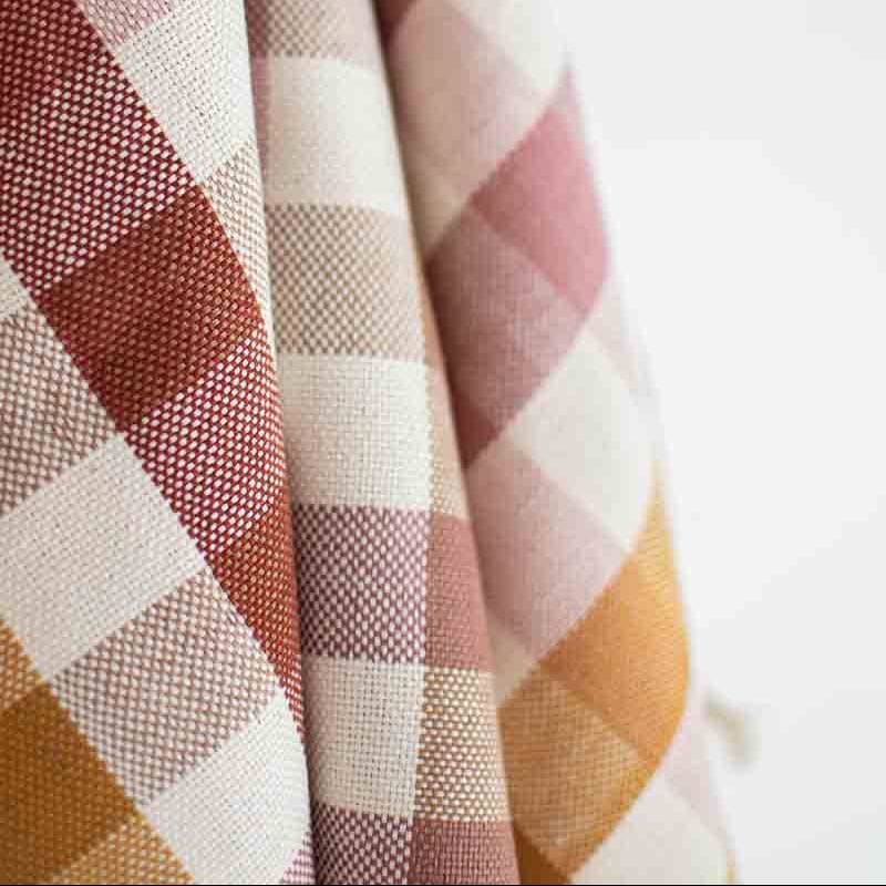 Close-up of checkered fabric with red, white, and orange pattern on a light background
