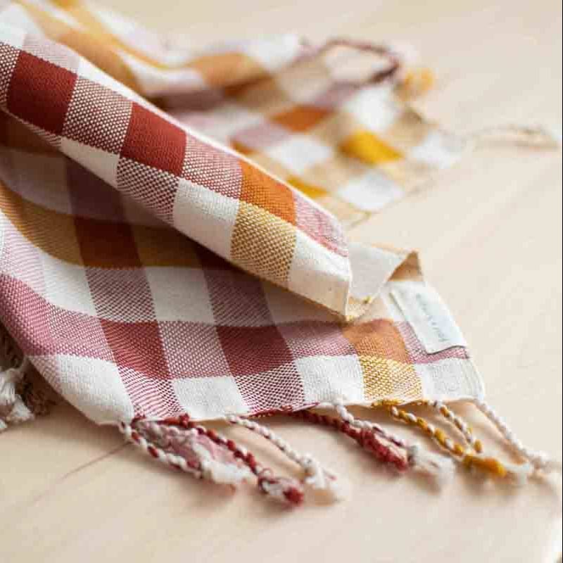 Plaid towel with fringes on a wooden surface