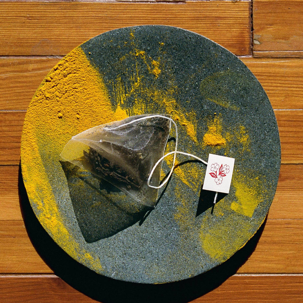 Tea bag with a tag on a round stone coaster against a wooden background