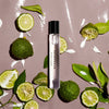 Perfume bottle labeled 'Bergamusk' surrounded by green limes and leaves on a beige background