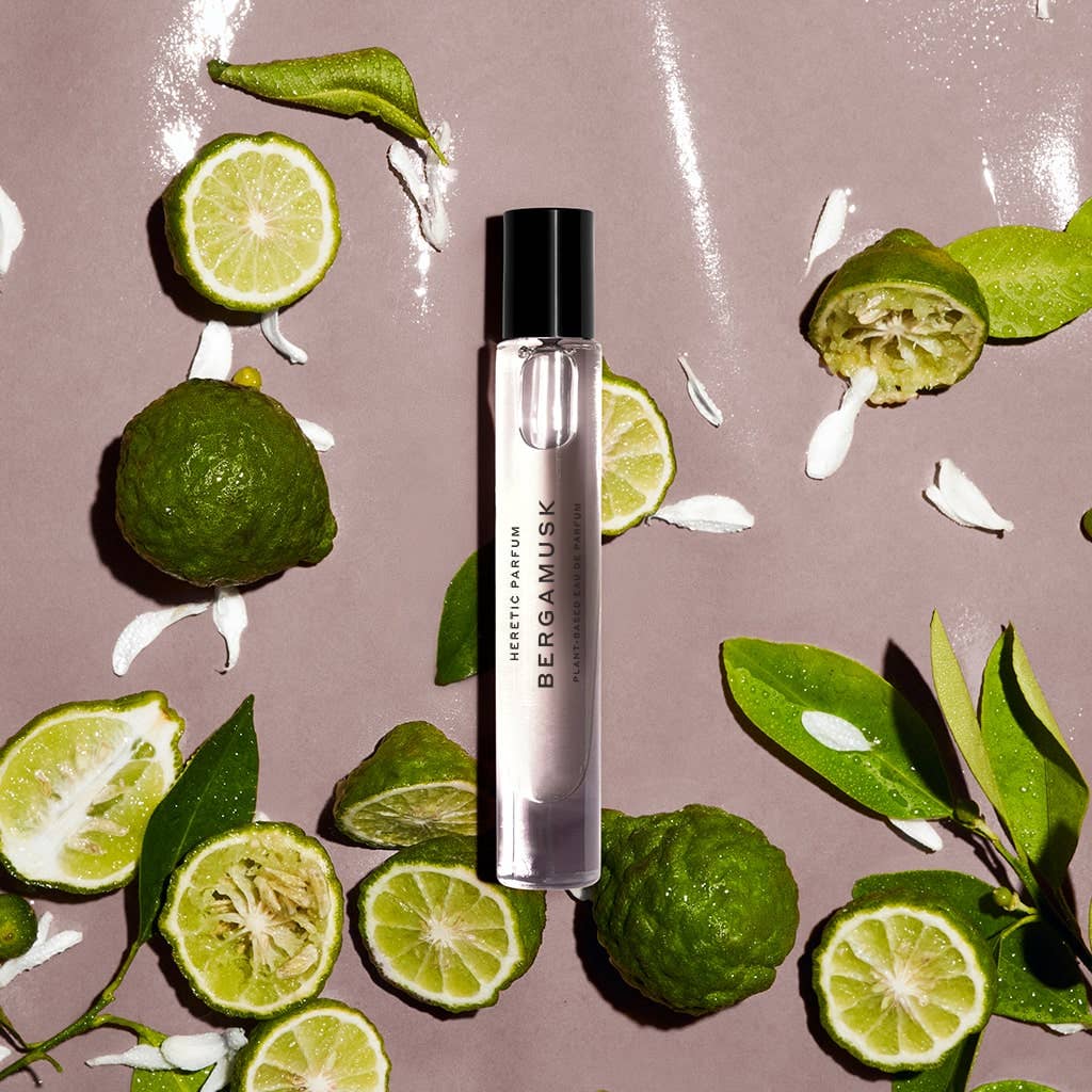 Perfume bottle labeled 'Bergamusk' surrounded by green limes and leaves on a beige background