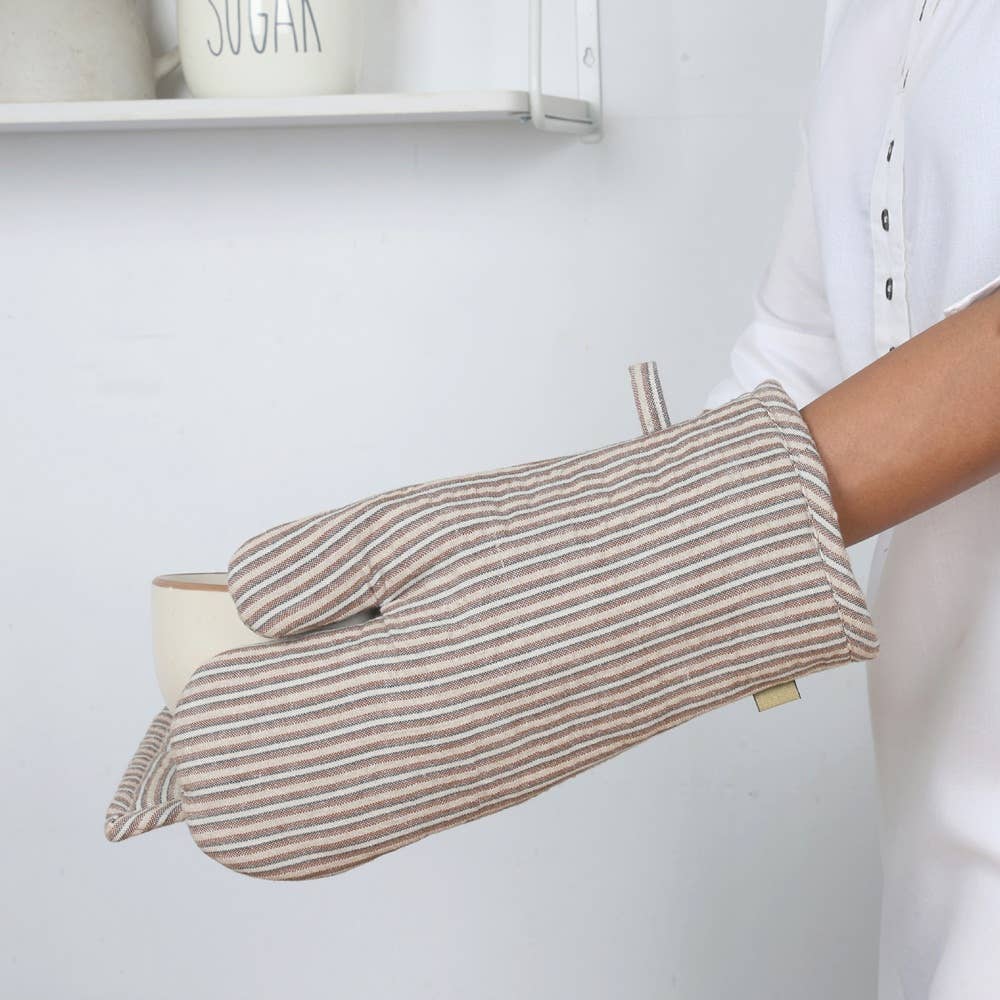 Person wearing a beige and brown striped oven mitt in a kitchen setting.