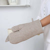 Person wearing a beige and brown striped oven mitt in a kitchen setting.