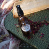 Brown glass bottle with a label on a green textured surface with dried flowers and a floral cloth.