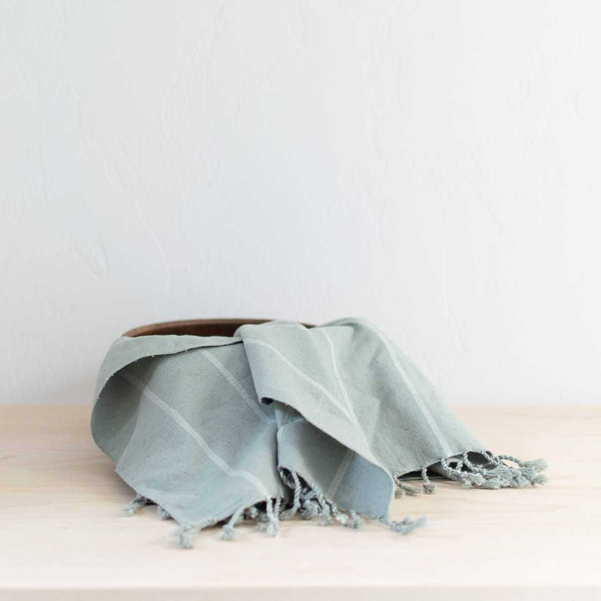 Light blue towel with frayed edges on a wooden surface against a light gray background