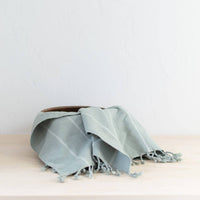 Light blue towel with frayed edges on a wooden surface against a light gray background