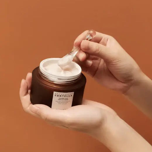 Hand holding a jar of cream with a brown background