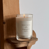 Candle in a glass jar with a label on a wooden shelf