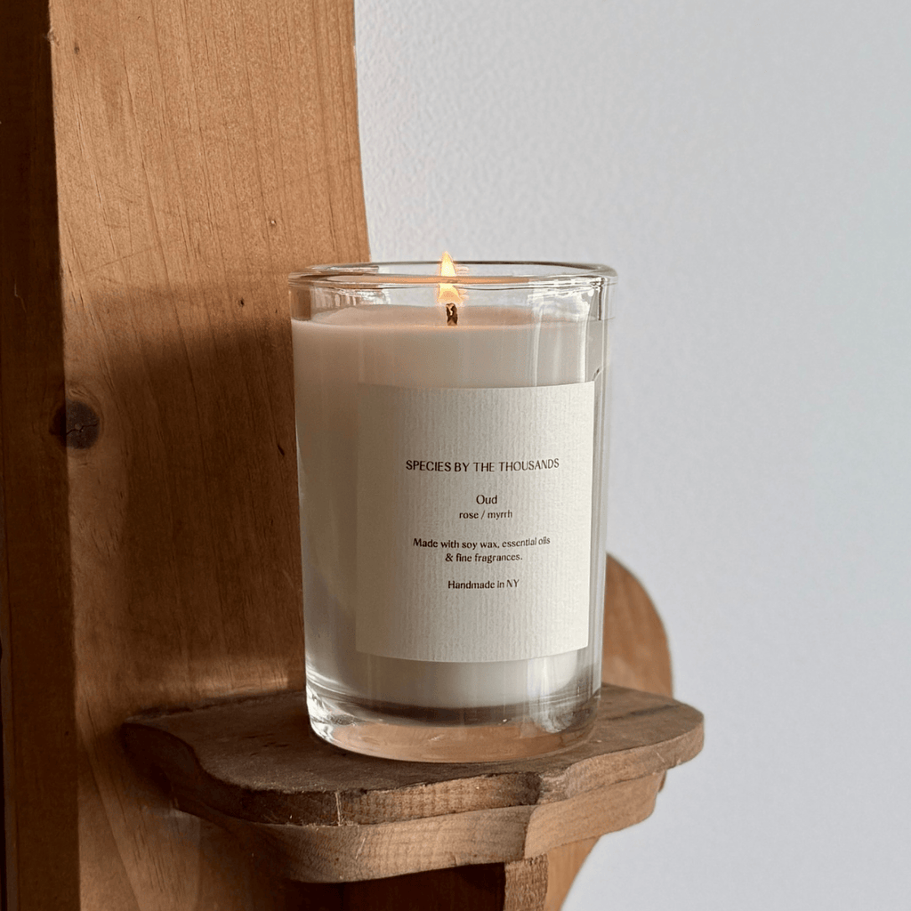Candle in a glass jar with a label on a wooden shelf