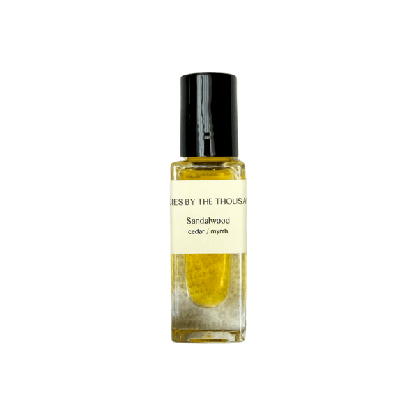 Sandalwood essential oil bottle with a black cap on a white background