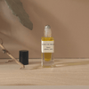 Small glass bottle with yellow liquid on a beige surface with a neutral background