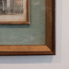 Framed artwork with a detailed brown frame on a light gray wall.