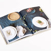 Open book showing images of table settings and food on a white background