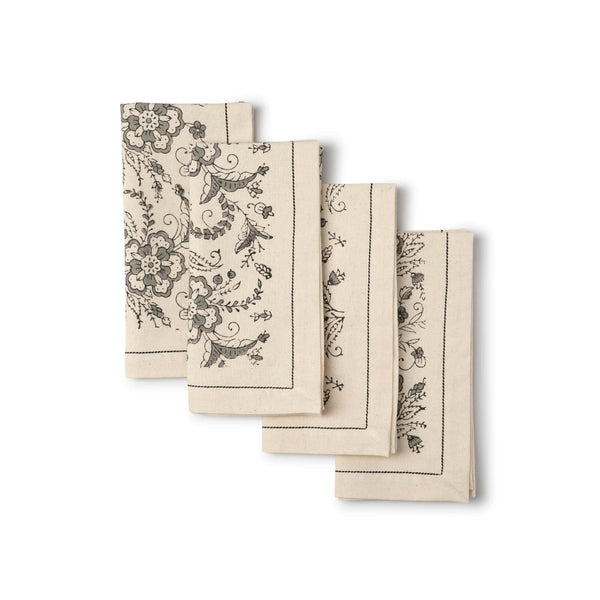 Set of four beige napkins with black floral patterns on a white background