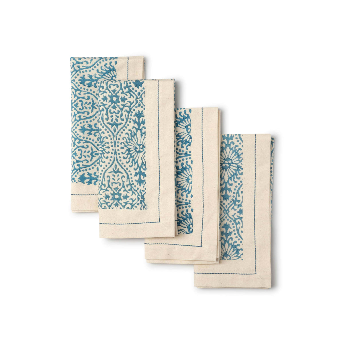 Set of four blue and white patterned napkins on a white background
