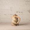 Ceramic teapot with brown and beige patterns on a textured beige background