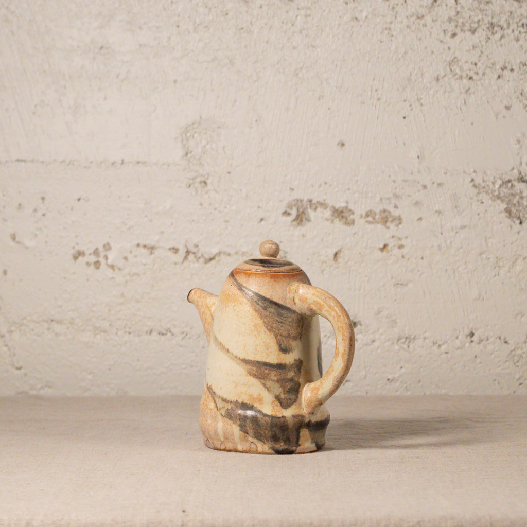 Ceramic teapot with brown and beige patterns on a textured beige background