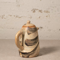 Ceramic teapot with abstract design on a textured surface