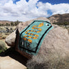 Textile with a snake design draped over a rock in a desert landscape