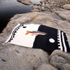 Blanket with fish design on rocks by a river