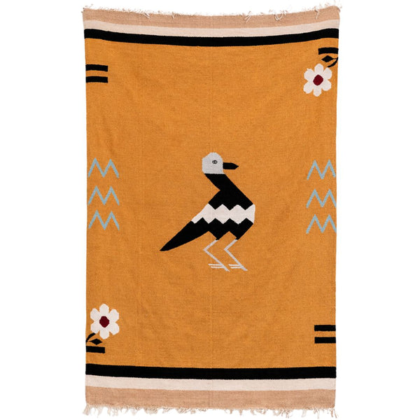 Orange blanket with a black and white bird design and floral elements on a white background