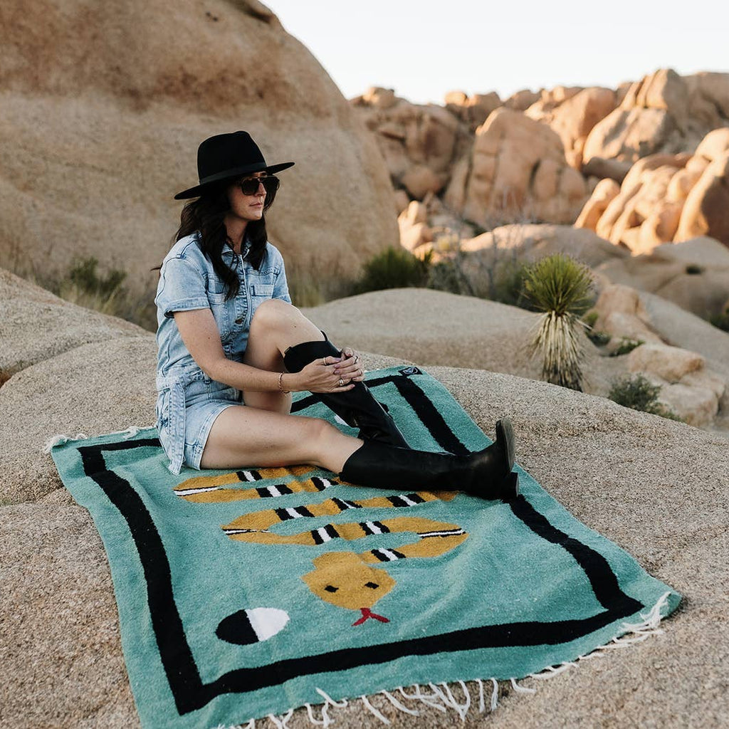 Woman sitting on a colorful rug with desert landscape in the background